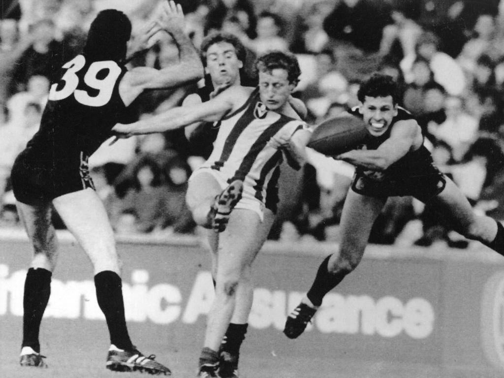 North Melbourne’s Rohan Robertson kicks the ball as he is tackled by Carlton’s Adrian Gleeson and Warren McKenzie at The Oval in London during 1987. Picture: AP