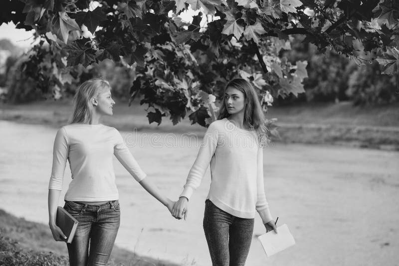 two-young-girls-hold-hands-two-young-girls-best-friends-hold-hands-walking-along-river-summer-day-green-park-133596443.jpg