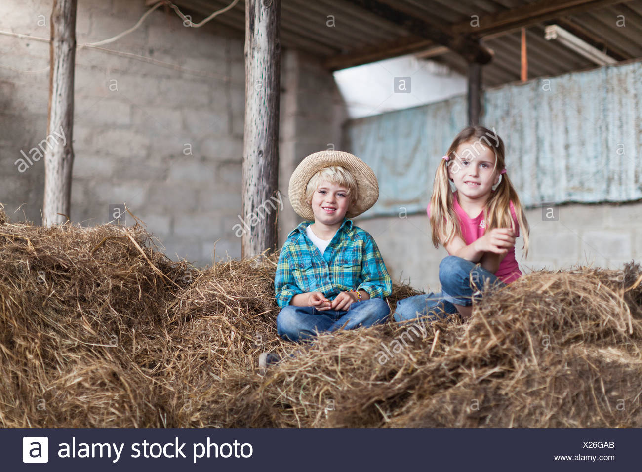 children-sitting-in-haystack-in-stable-X26GAB.jpg