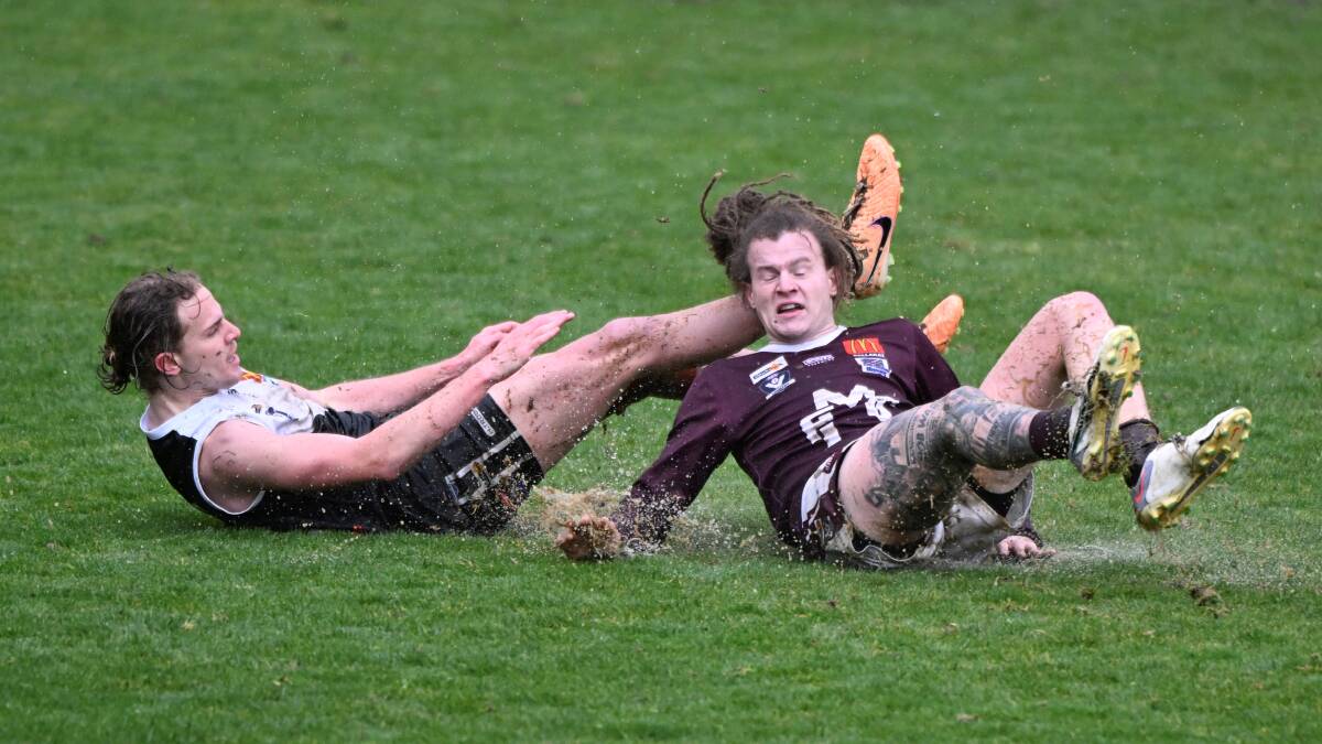 Max Faulkner of North Ballarat and Conrad Farrugia of Melton slip through the surface at Mars Stadium on Saturday. Picture by Lachlan Bence