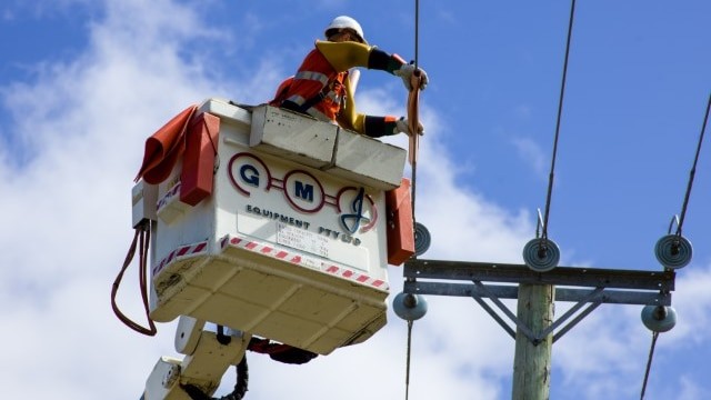 A worker in Hi-Vis working on a powerline.